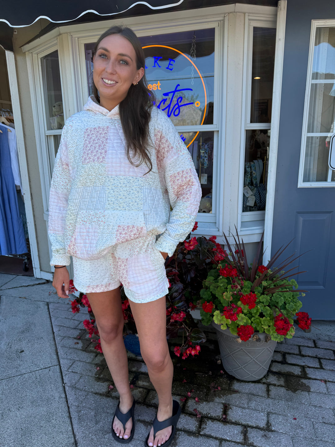 Person wearing quilted hoodie sweatshirt and matching quilted drawstring shorts in pastel pink and blue stripes and floral quilting square patterns.