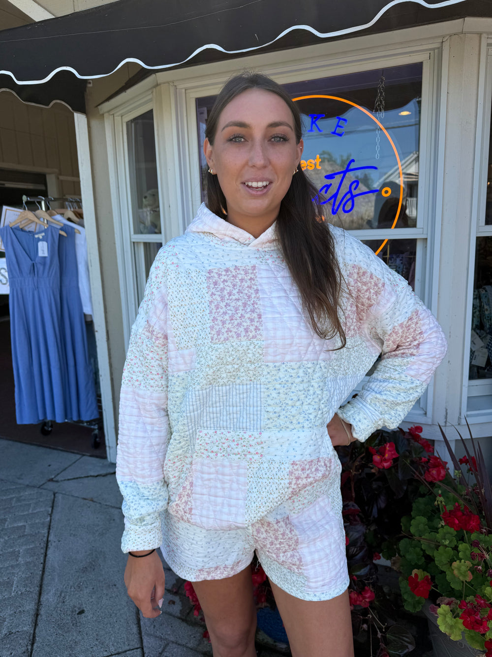 Person wearing quilted hoodie sweatshirt and matching quilted drawstring shorts in pastel pink and blue stripes and floral quilting square patterns.
